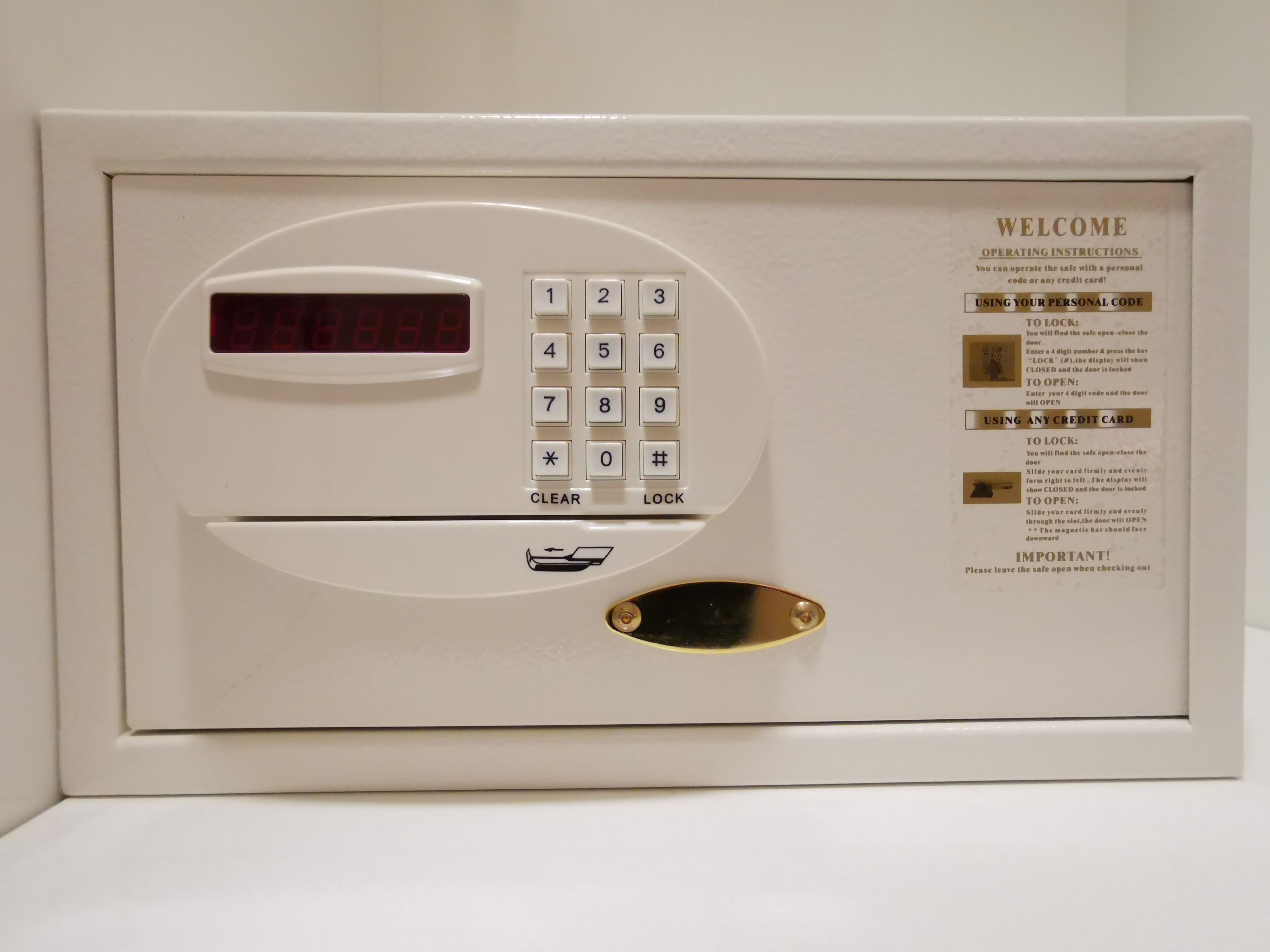 Un coffre-fort blanc doté d’un clavier, d’un écran numérique et d’un manuel d’utilisation.