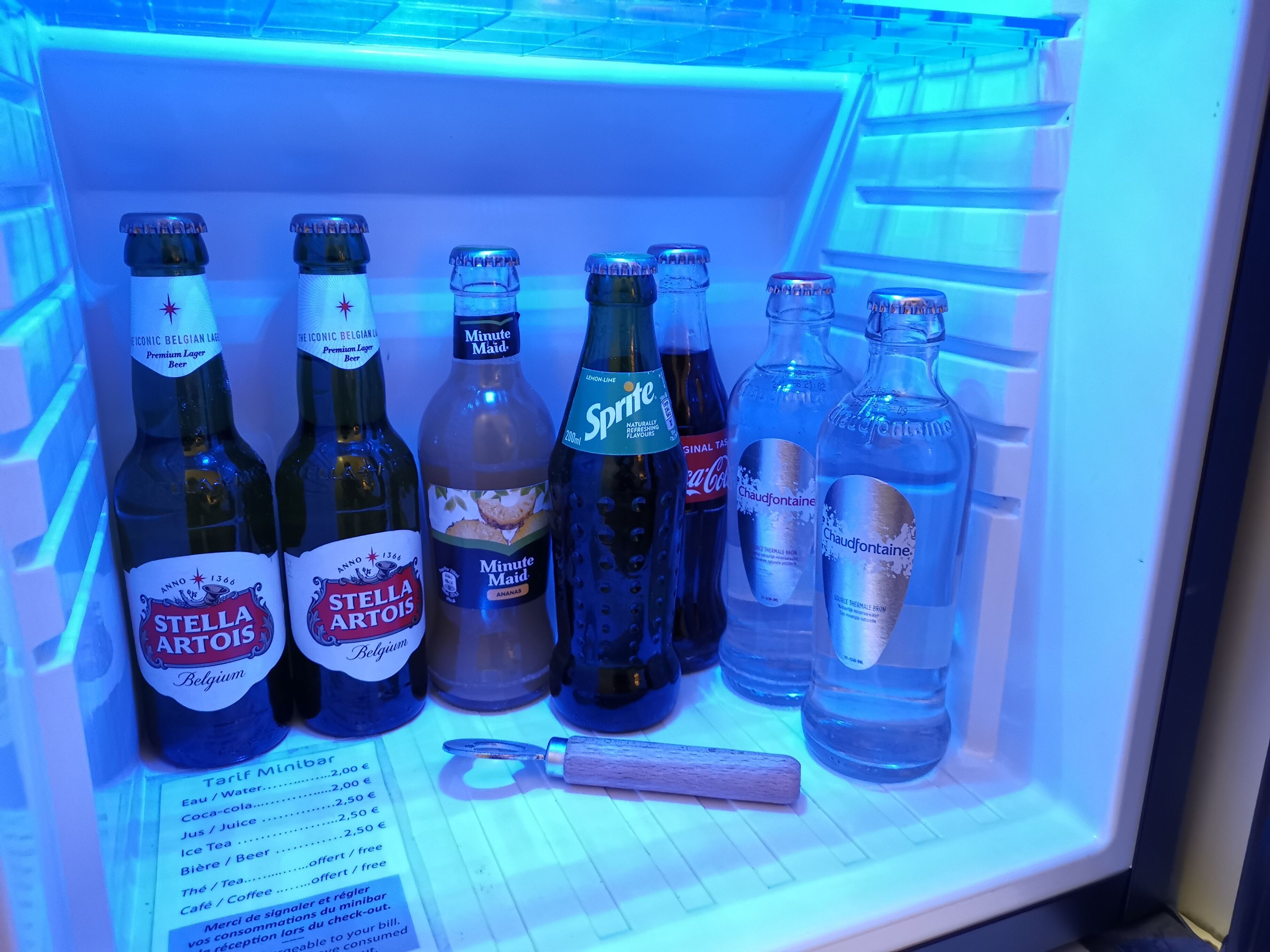 Een koelkast gevuld met verschillende drankjes, waaronder Stella Artois, Minute Maid, Sprite en Chaudfontaine.