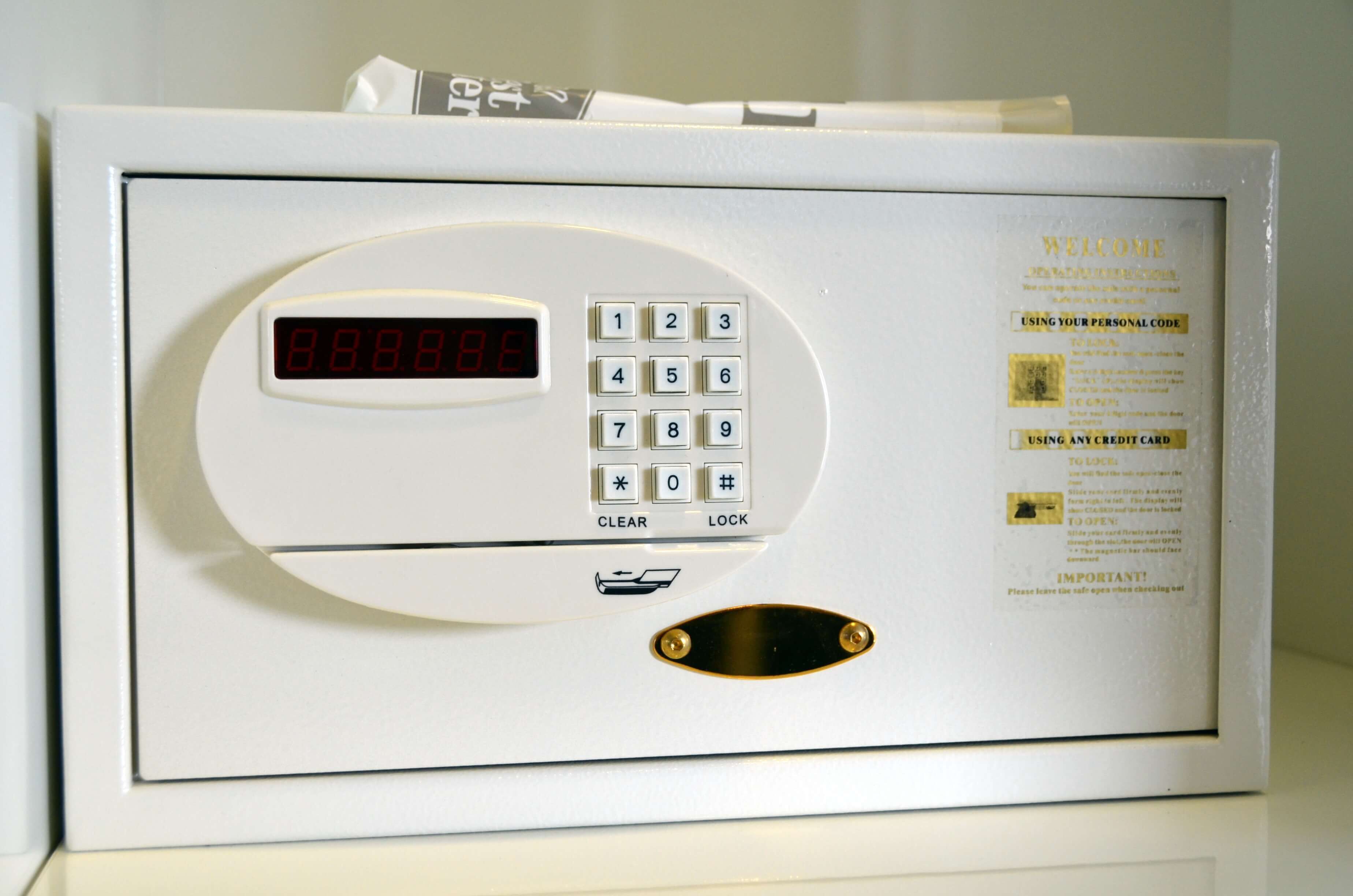 Ein weißes elektronisches Gerät mit Tastenfeld, Digitalanzeige und einer kleinen Schlitze, vermutlich ein Zutrittssystem für Hotelzimmer.