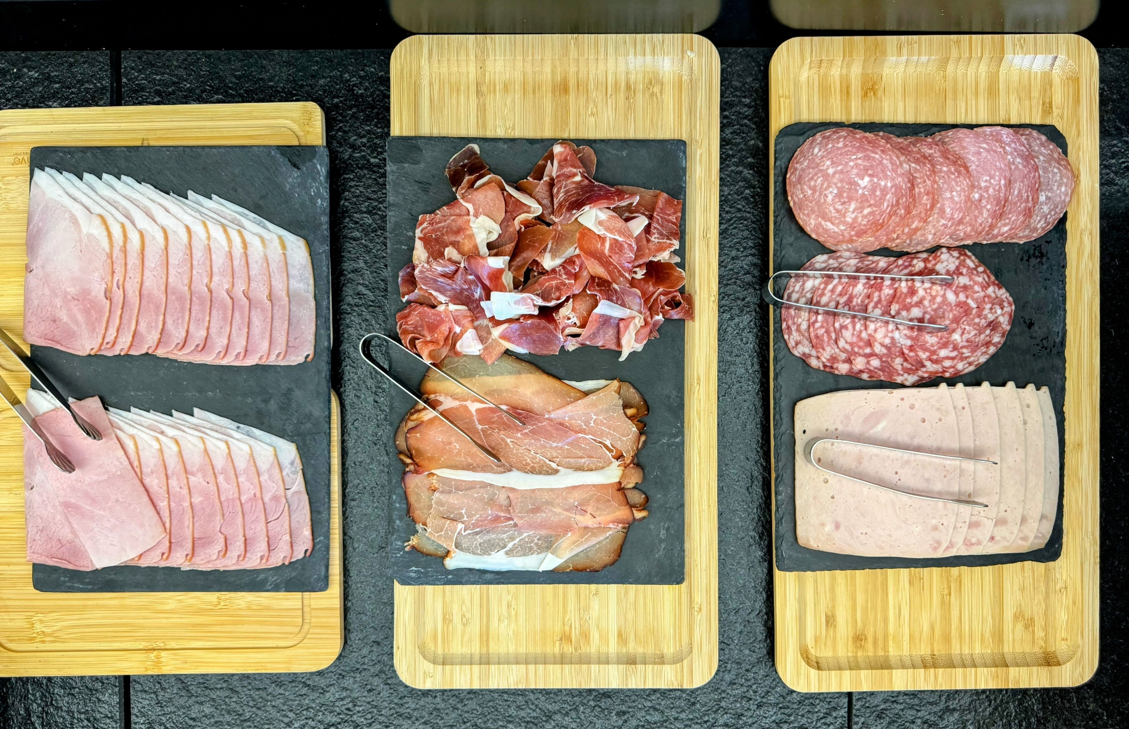 Three wooden cutting boards with different types of meat.