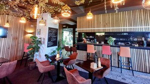 Un restaurante con paredes de paneles de madera, lámparas colgantes y una zona de bar con taburetes.