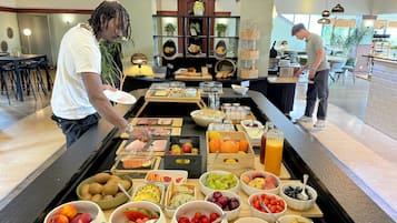 Una mesa de buffet con diferentes alimentos y una persona sirviendo.