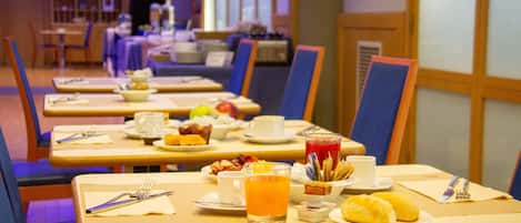 Una colazione allestita con tavoli pronti per consumare, inclusi piatti di cibo, tazze e un bicchiere di succo d'arancia.