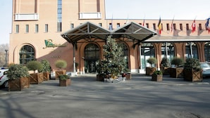A hotel entrance with a Christmas tree, brick facade, and flags. - Pacific Hotel Fortino (Turin)