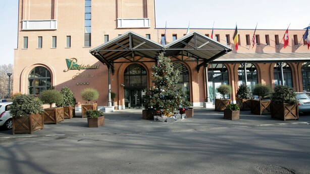 Fachada de hotel con un árbol de Navidad y banderas.