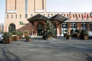 A hotel entrance with a Christmas tree, brick facade, and flags. - Pacific Hotel Fortino (Turin)
