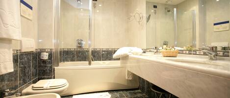 A modern bathroom with a bathtub, a large mirror, a sink, and a toilet.