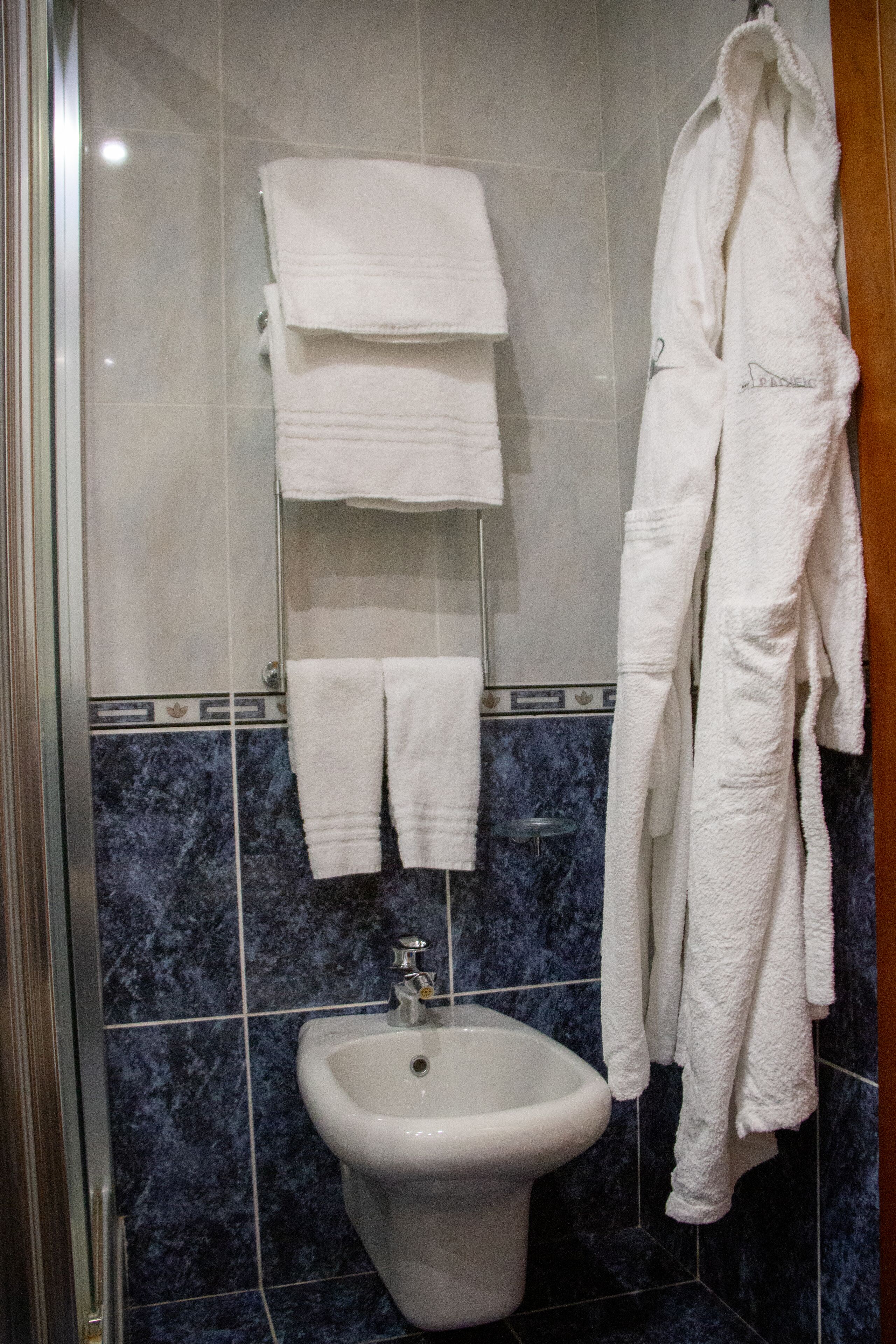 Ein Badezimmer mit Waschbecken, einem Handtuchhalter mit mehreren Handtüchern und einem Bademantel an der Wand.