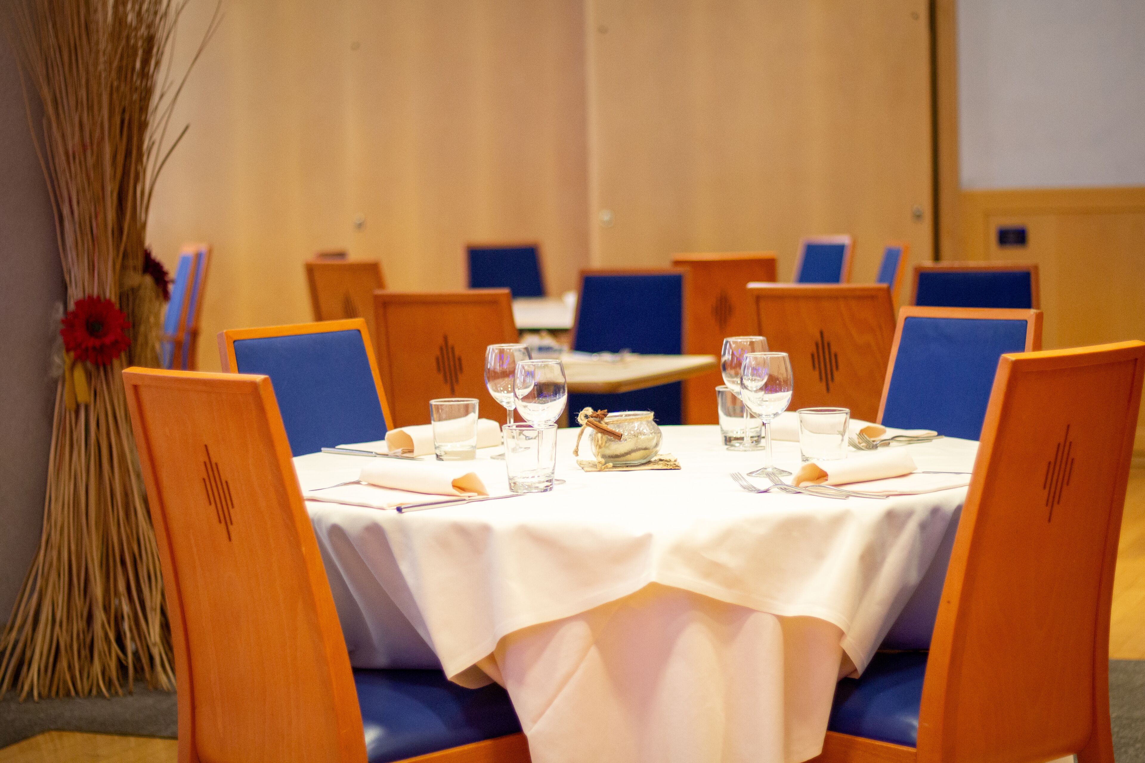 A conference room with a round table, blue chairs, and a white tablecloth.