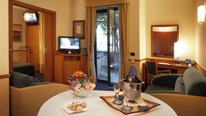 Habitación de hotel con comedor, televisor, minibar y vistas al exterior.