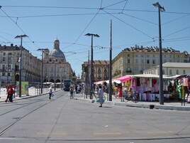 Eine Straße mit Straßenbahnschienen, einer Straßenbahn und Fußgängern.