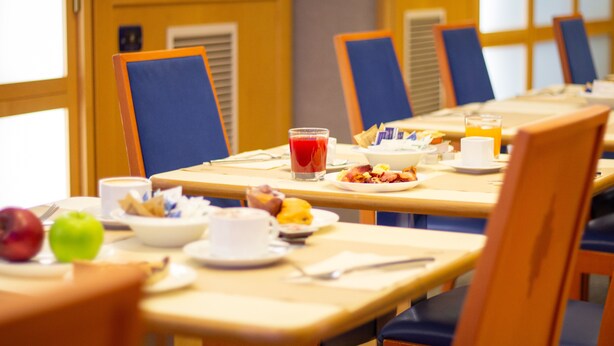 A breakfast setting with tables, chairs, and various breakfast items. - Pacific Hotel Fortino (Turin)