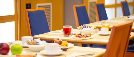 Un ambiente para desayunar con mesas, sillas y diferentes opciones para el desayuno.