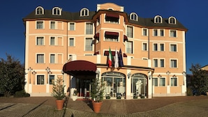 Een hotel met meerdere verdiepingen, een centrale ingang, grote ramen en een rode luifel.