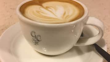 En kopp kaffe med vackra mönster i mjölkskummet, serverad på ett litet fat.