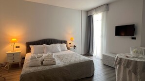 Een hotelkamer met een groot bed, nachtkastjes, een televisie en een tafeltje met een vaas.