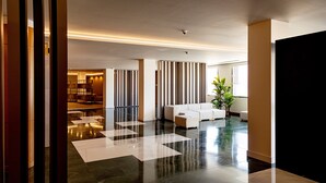 Un hall d’entrée moderne avec un sol à carreaux noirs et blancs, un canapé blanc et des cloisons à rayures.