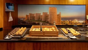 Un buffet de petit-déjeuner avec des viennoiseries et, en arrière-plan, une grande fresque murale sur le thème d’un château.