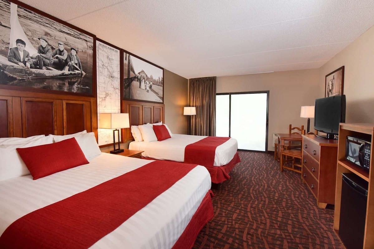 Une chambre d’hôtel avec deux lits, une télévision, un bureau et une fenêtre.
