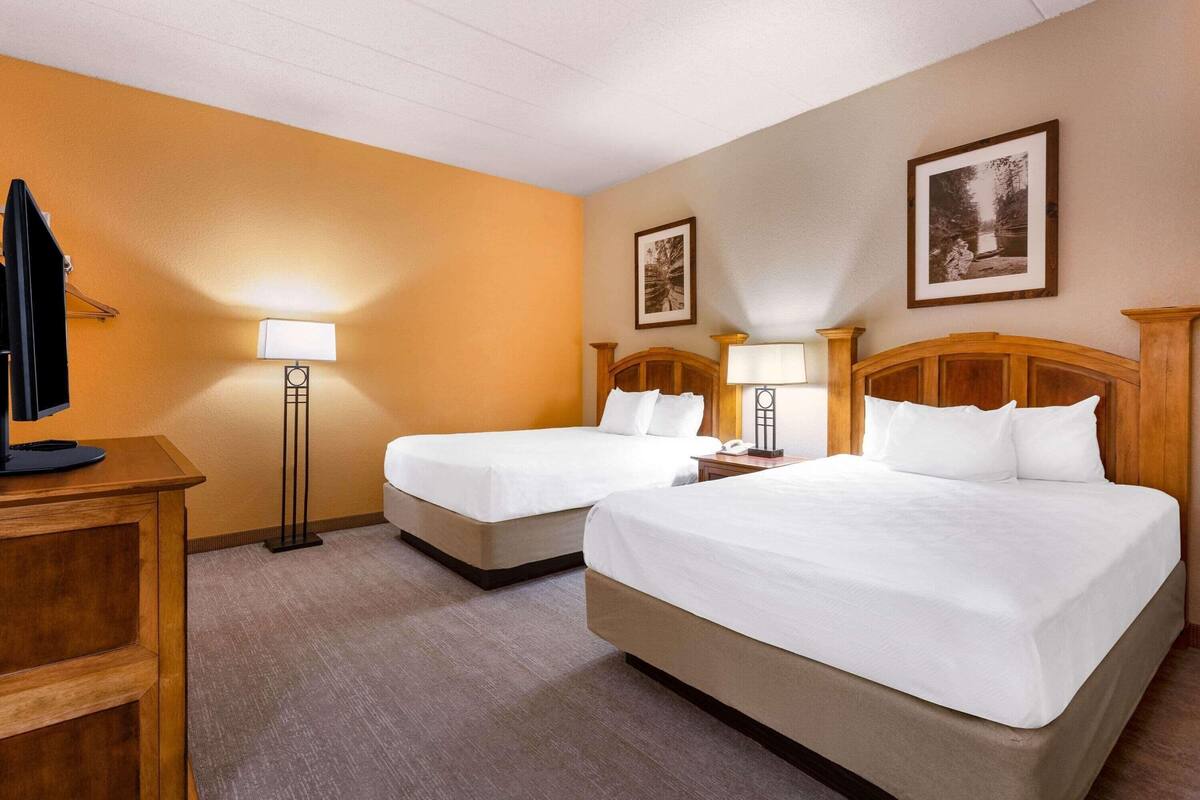 Une chambre d’hôtel avec deux lits, un bureau, une télévision et une lampe.