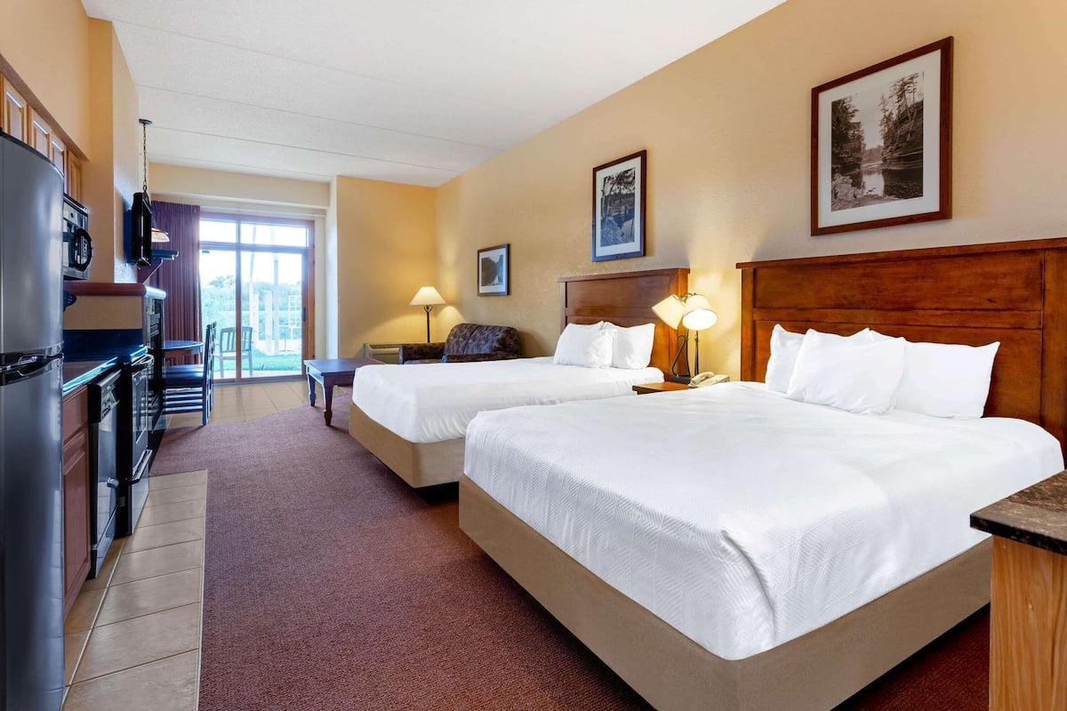 Une chambre d’hôtel avec deux lits, une kitchenette, un coin repas et une grande fenêtre.