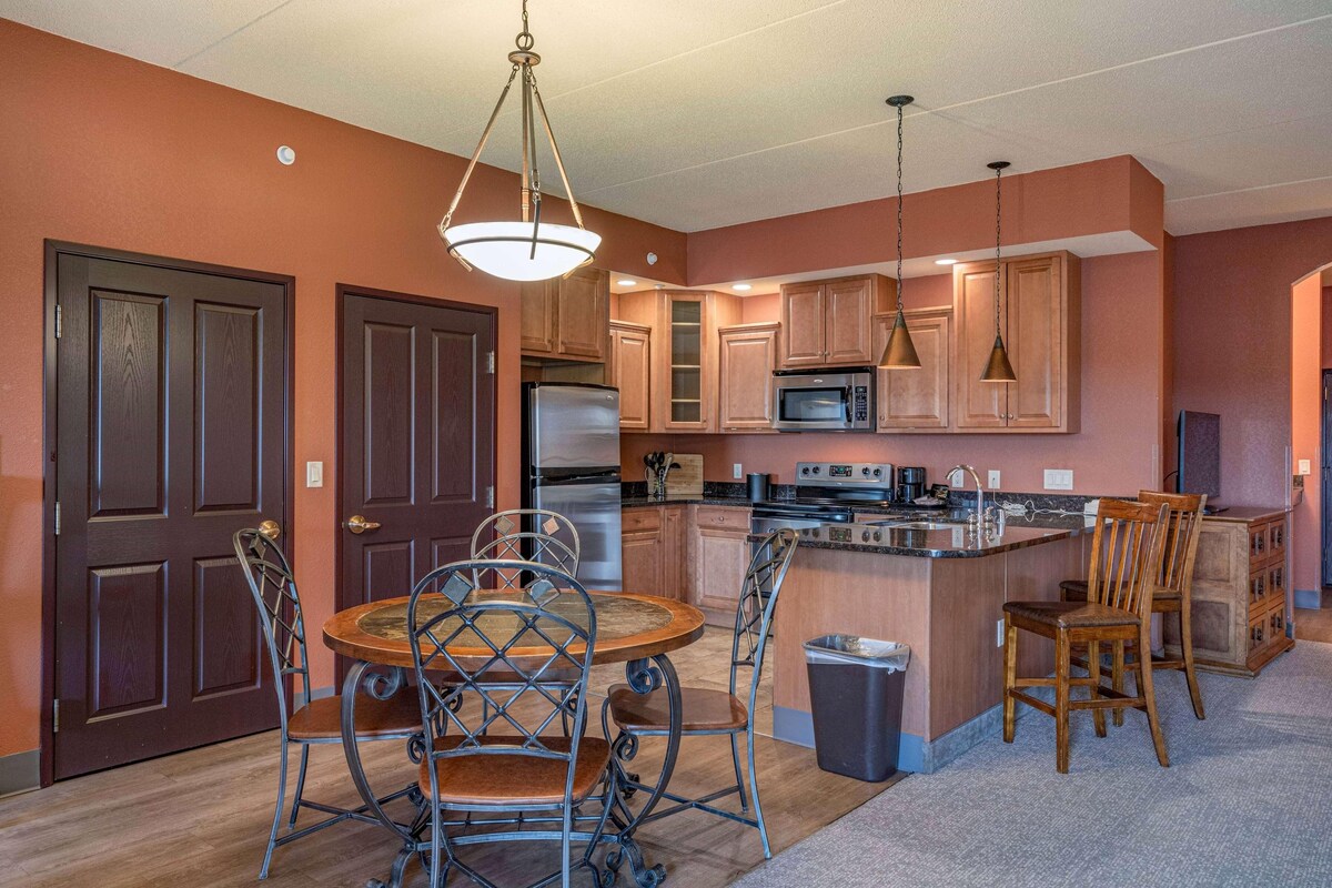 A modern kitchen with a central island, stainless steel appliances, and a dining area with metal chairs.