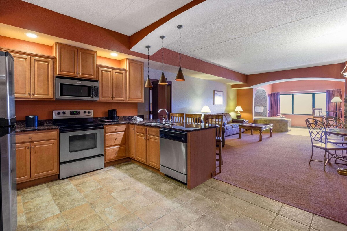 A modern kitchen with stainless steel appliances, wooden cabinets, and pendant lighting.