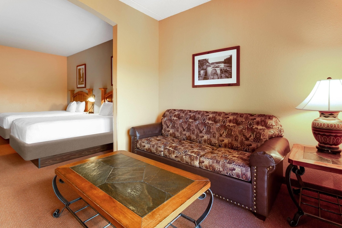 A hotel room with a bed, a sofa, a coffee table, a lamp, and a framed picture on the wall.
