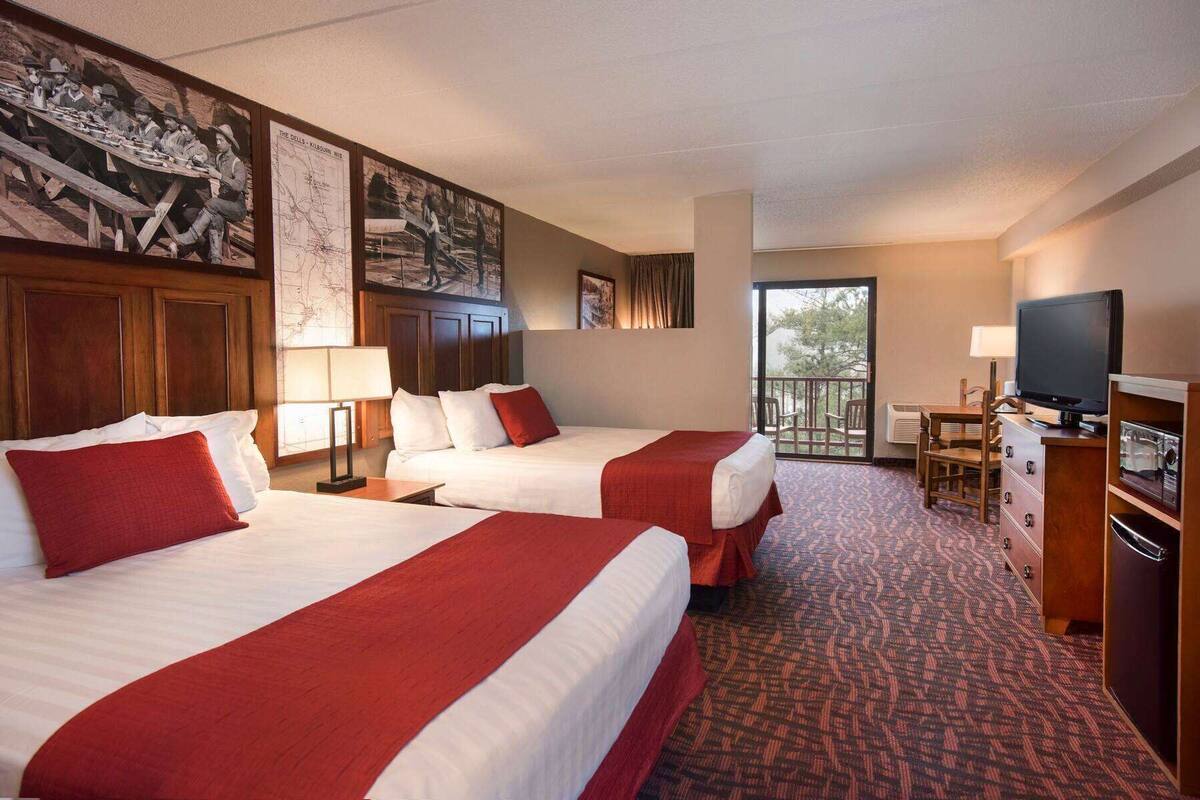 Une chambre d’hôtel avec deux lits, une télévision, un bureau et un balcon.
