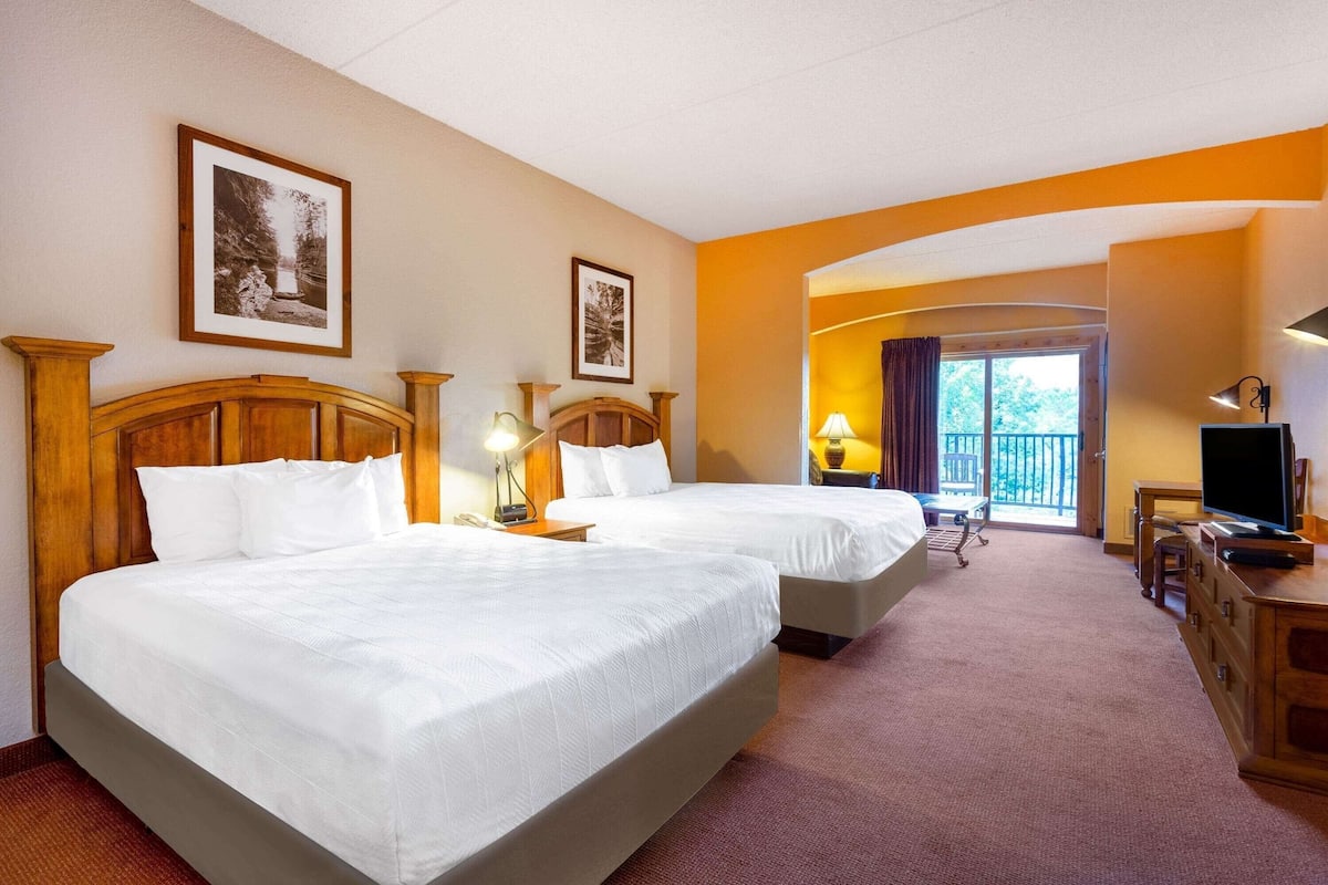 Une chambre d’hôtel avec deux lits, un bureau, une télévision et un balcon avec vue.