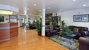 A spacious lobby with a reception desk, leather sofas, a coffee table, and a stone fireplace. - Microtel Inn & Suites by Wyndham Eagle River/Anchorage Area (Eagle River)