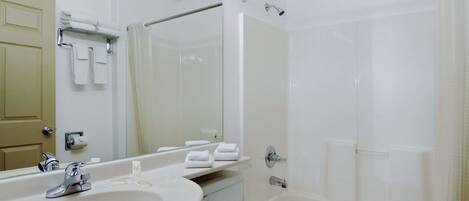 Un baño con lavamanos, espejo, toallero y bañera.