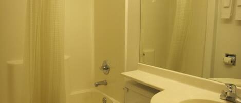 A bathroom with a bathtub, toilet, sink, and a mirror.