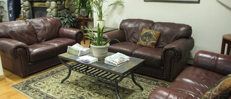 A living room with two leather sofas, a coffee table, and a patterned rug.