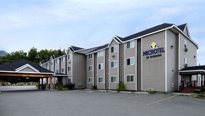 A Microtel by Wyndham hotel with a covered parking area and a stone facade. - Microtel Inn & Suites by Wyndham Eagle River/Anchorage Area (Eagle River)