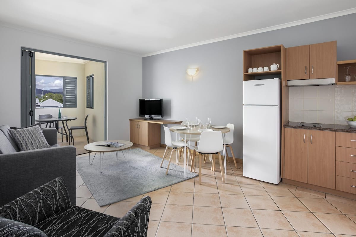 A modern apartment with a dining area, kitchen, and a balcony with a view.