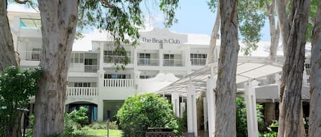 A white building with balconies and a sign reading "The Beach Club".