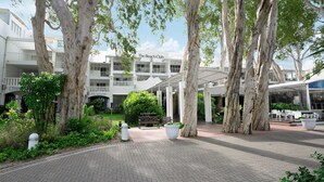 Un hotel con un espacio exterior cubierto, árboles y un cartel que dice "The Beach Club".