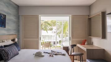 Una habitación de hotel moderna con cama, escritorio y balcón con vistas a palmeras.