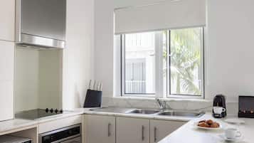 A modern kitchen with a built-in stove, oven, and sink. There is a window with a view of palm trees outside.