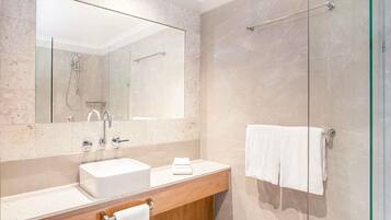 Un bagno moderno con uno specchio grande, un lavandino, una doccia e un box doccia in vetro.