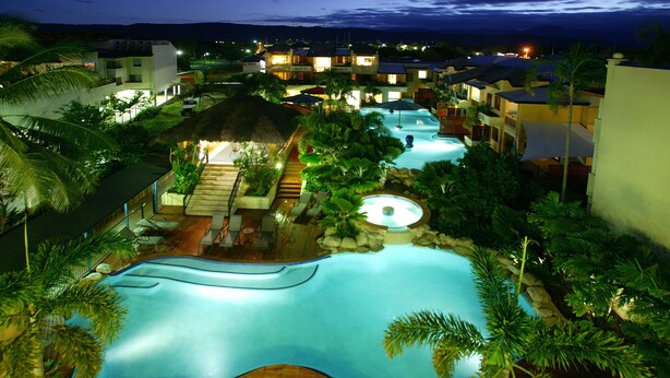 A resort with multiple swimming pools, palm trees, and well-lit buildings. - Mantra Heritage (Port Douglas)