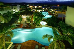 A resort with multiple swimming pools, palm trees, and well-lit buildings. - Mantra Heritage (Port Douglas)