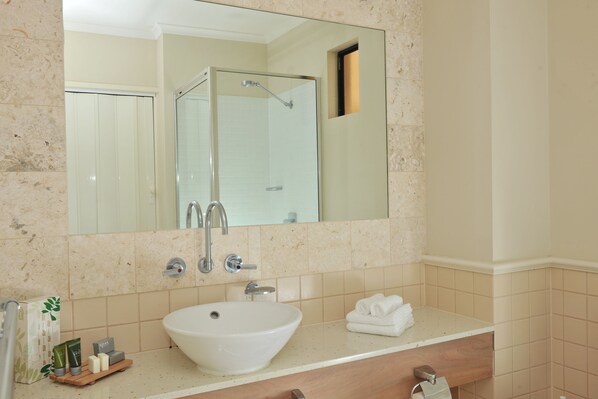A bathroom with a large mirror, a sink, and a shower. - Mantra Heritage (Port Douglas)