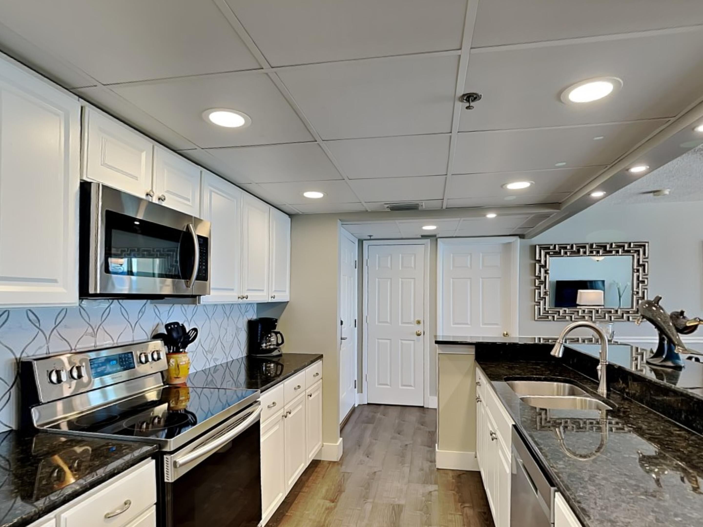 A modern kitchen with white cabinets, stainless steel appliances, and a black countertop.