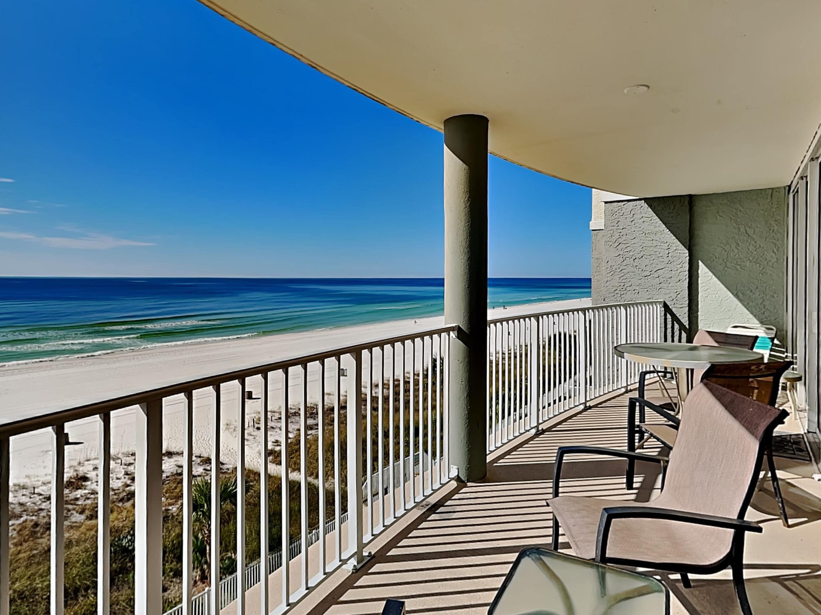 A balcony with a view of the beach and ocean.