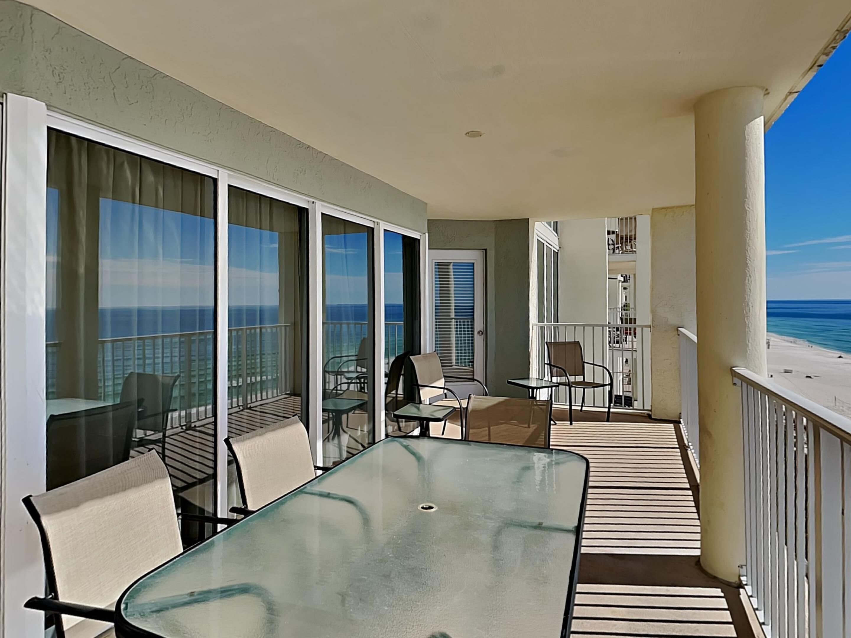 Ein Balkon mit Glastisch und Stühlen, Blick auf den Ozean und einer Geländer.