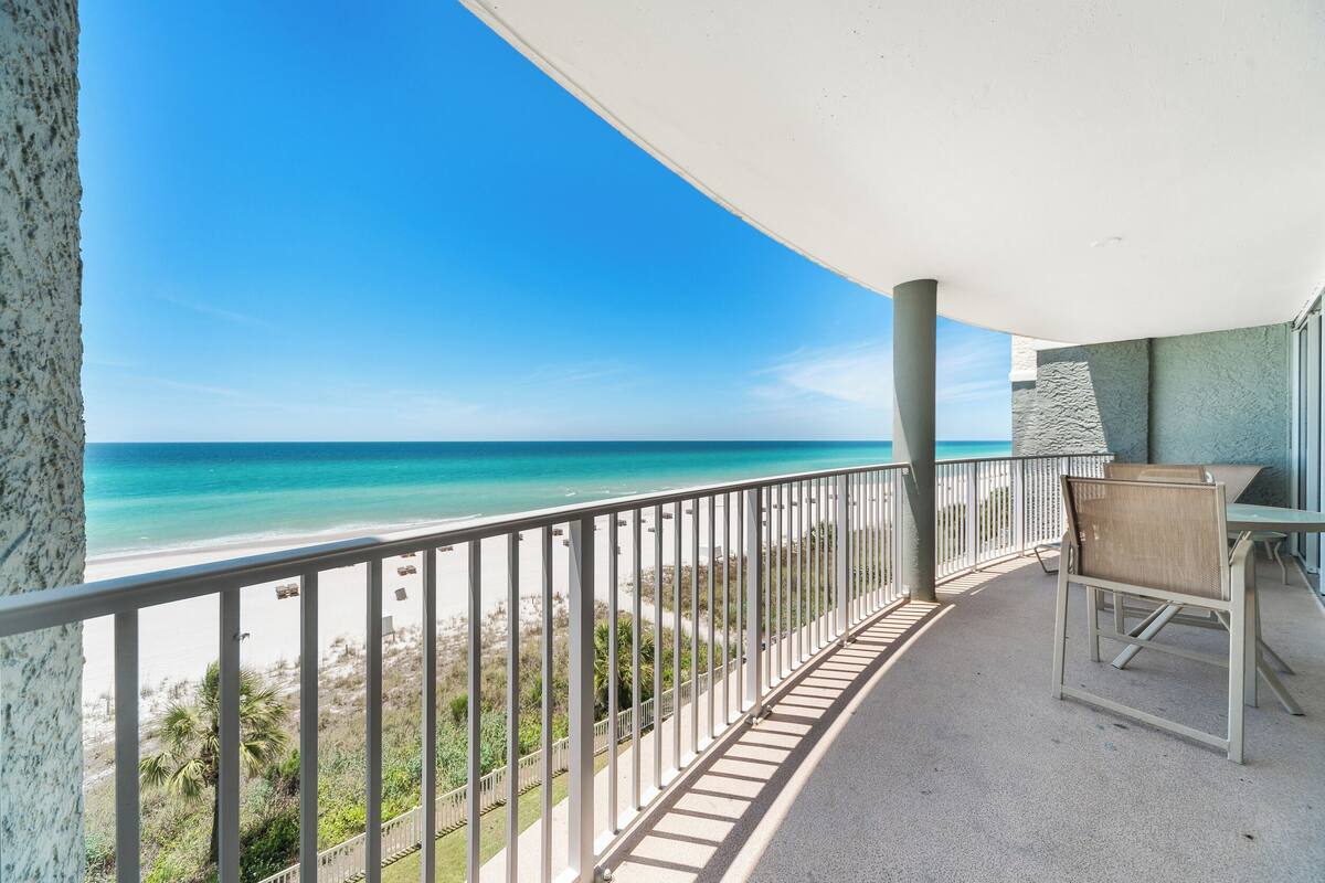 A balcony with a view of the beach and ocean.
