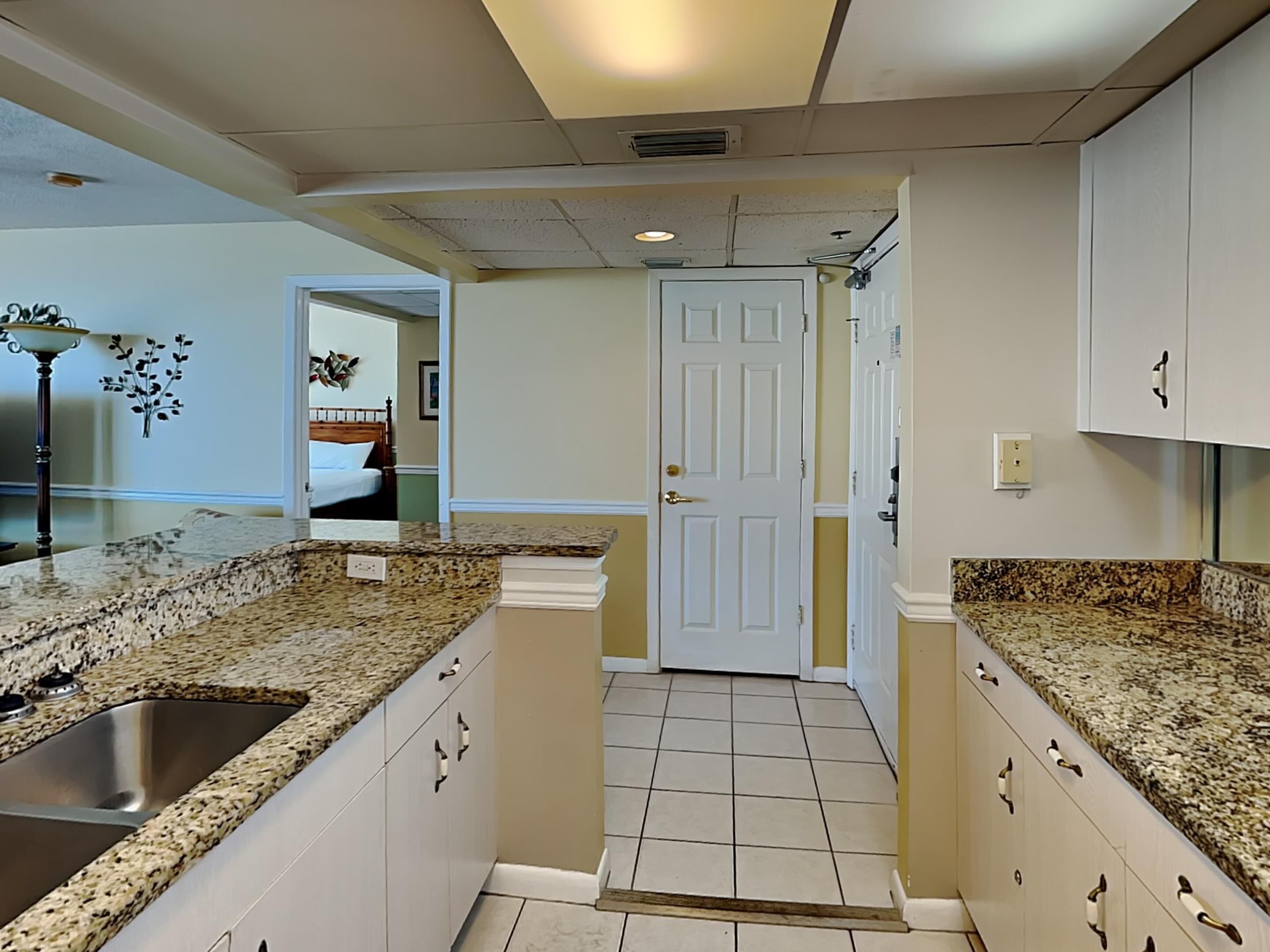 A kitchen with granite countertops, a stainless steel sink, and white cabinetry.