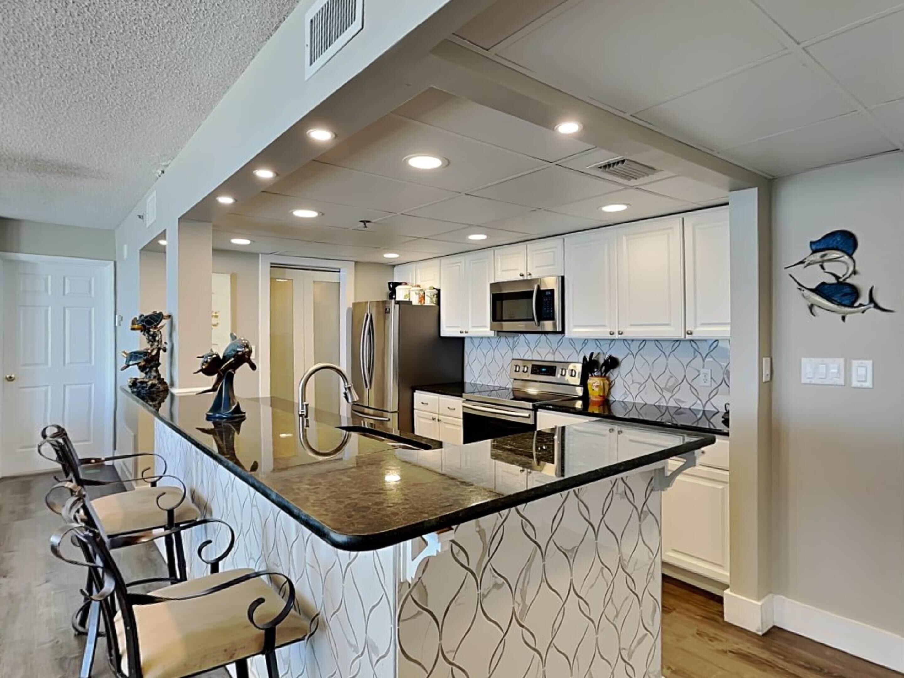 A modern kitchen with a central island, stainless steel appliances, and a patterned backsplash.